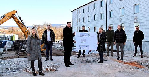 Pressebild zum begleitenden Text mit Gruppe vor Abrissarbeiten an der Berufsschule